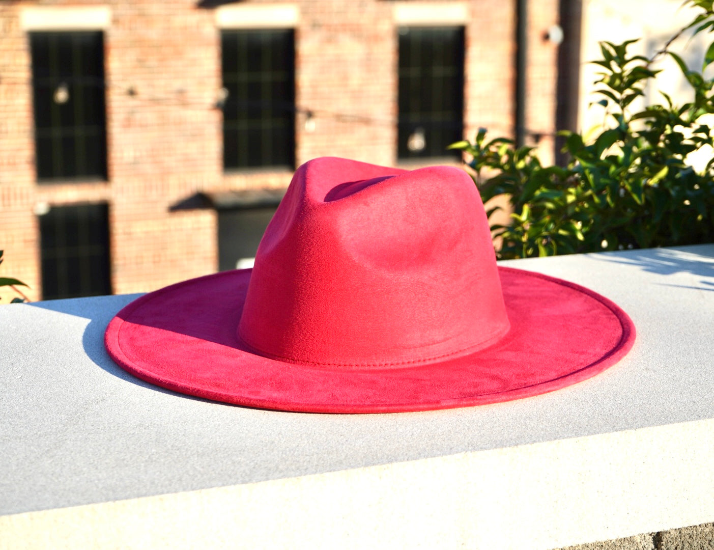 A womens suede wide brim fashion hat in a watermelon pink color.